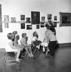 Grayscale photo; Burris Laboratory School students from 1962 view wall art at DOMA